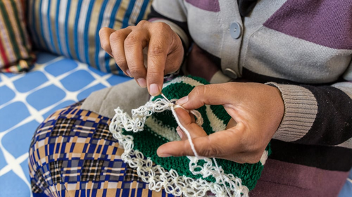 A young woman sews green and white fabric.